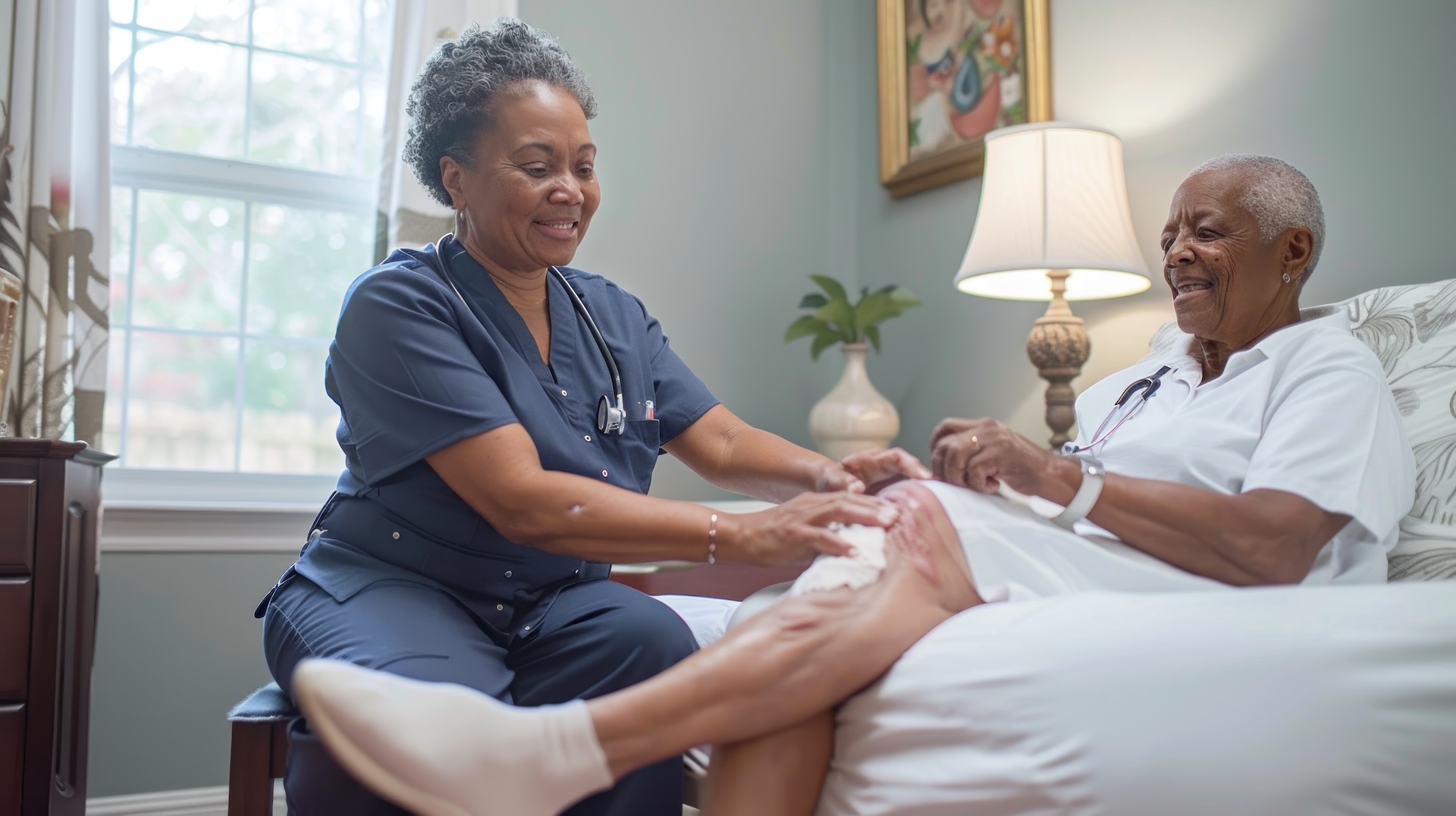 A dedicated home healthcare worker providing wound care for a senior woman. They are in a clean and well-lit bedroom, with the worker carefully dressing a wound on the woman’s leg. The woman looks